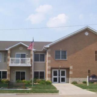 A two-story residential building with a brick exterior and an American flag at the entrance.