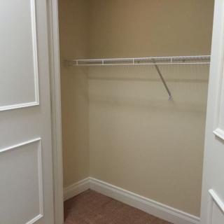 An empty indoor closet with a single shelf and hanging rod.