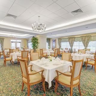 An elegant dining room with neatly set tables and chandeliers.