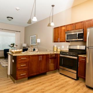A modern kitchen with wooden cabinets, stainless steel appliances, and an open layout.