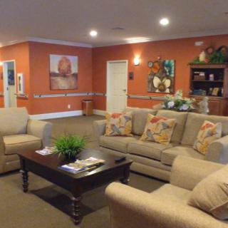 A cozy living room with comfortable sofas, a coffee table, and vibrant artwork on orange-painted walls.