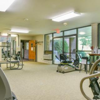 A spacious gym with various exercise equipment and large windows.