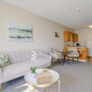 A cozy open-plan living area with a sofa, round table, and chairs leading into a compact kitchen.