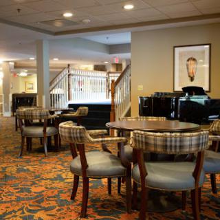 A cozy lounge area featuring round tables and comfortable chairs, complemented by decorative carpet and ambient lighting.