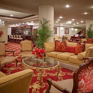 A luxurious hotel lobby featuring plush seating, elegant decor, and a grand piano.