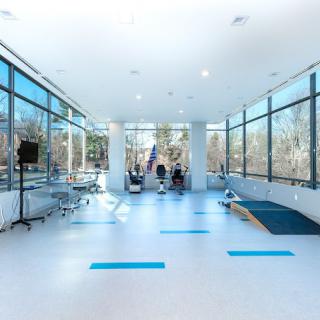 A spacious and modern room with large windows, minimalist design, and an exercise area.