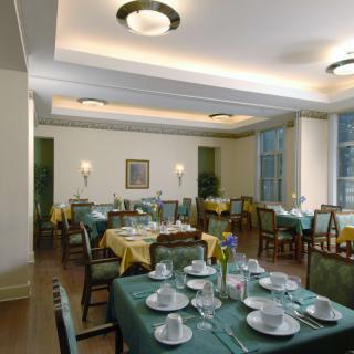 A well-arranged dining room with tables set for service, featuring elegant lighting and decor.