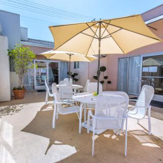 A serene outdoor patio area featuring white furniture and large umbrellas, perfect for enjoying a sunny day.