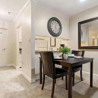 A modern dining area with a minimalist design, featuring a table and chairs, a decorative wall clock, and a large mirror.