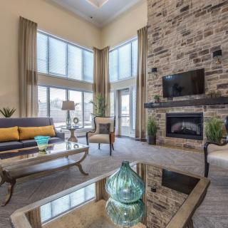 A modern living room with a stone fireplace and large windows, featuring stylish furniture and decor.