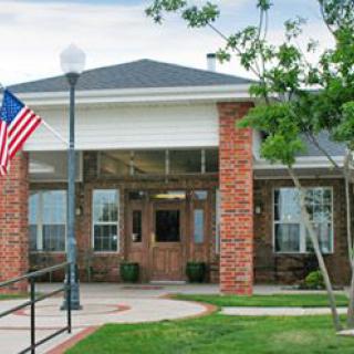 A suburban building entrance with a flag and brick facade.