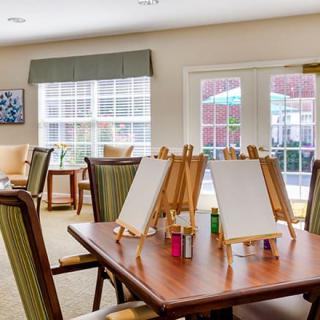 A bright art studio with easels and painting supplies set up on tables.