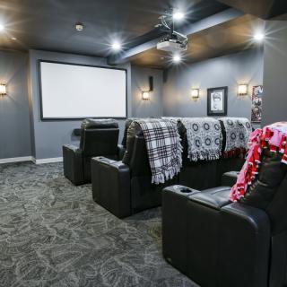 A cozy home theater setup with comfortable seating and a large projector screen.