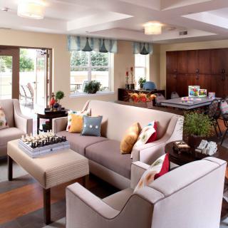 A cozy living room with modern furnishings, featuring a large sofa, decorative pillows, and ample natural light.