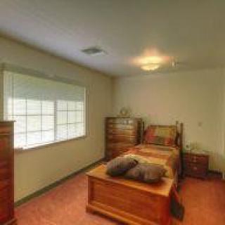 A cozy bedroom featuring wooden furniture and a large window.
