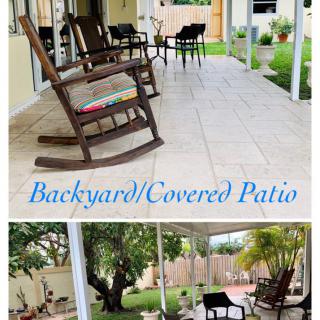 A cozy backyard with a covered patio featuring rocking chairs and outdoor seating, surrounded by a lush garden.