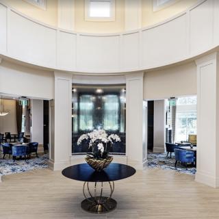 A modern lobby with a central circular table adorned with flowers, surrounded by elegant seating areas.