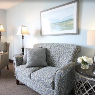 A cozy living room with a patterned sofa, armchairs, and elegant lighting.