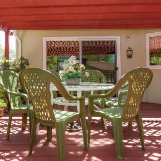 A sunny patio with green chairs and a table arranged for outdoor seating.