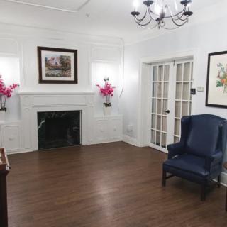 A cozy living room with a fireplace, elegant chandelier, and comfortable armchair.