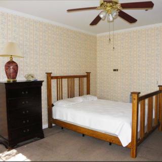 A bedroom with a wooden bed, dresser, and ceiling fan.