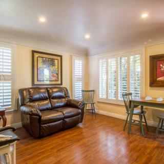 A cozy living room with a leather sofa and a dining area by the windows.