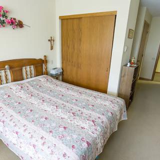 A cozy bedroom with a floral quilt on the bed and a wooden closet.