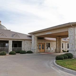 A stone facade building with a covered entrance and driveway.