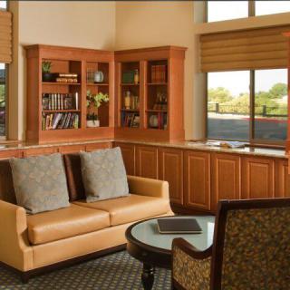 A cozy living room with a sofa, bookshelves, and large windows letting in natural light.