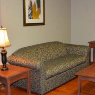 A cozy living room setup featuring a patterned sofa, wooden tables, and a lamp.