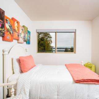 A cozy bedroom with colorful artwork and a window view.