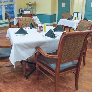 An elegantly set dining area with tables and chairs, featuring neatly arranged table settings.