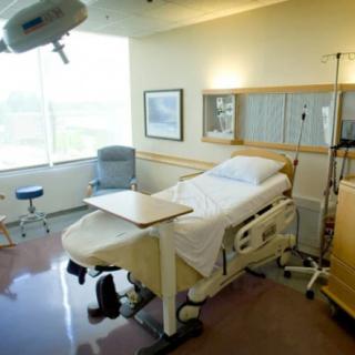 A clean and well-lit hospital room with a bed and medical equipment.