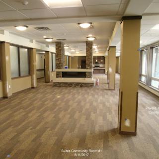 Spacious empty room with wooden flooring and large windows.