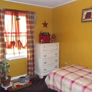 A cozy bedroom with yellow walls and plaid decor.