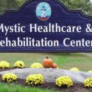 Sign for Mystic Healthcare & Rehabilitation Center with autumnal decorations.