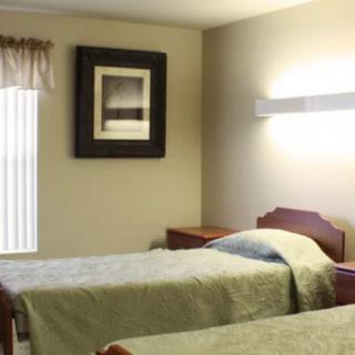 A simple bedroom with two twin beds, a nightstand, and wall art.