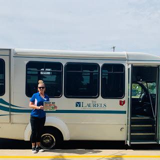 A woman stands beside a public transportation bus, ready for her next journey.