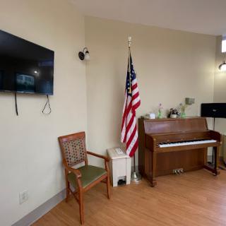 A cozy room featuring a piano, an American flag, a television, and a chair.
