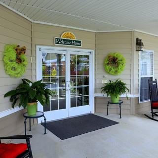 A welcoming porch with double doors, decorative plants, and comfortable seating.