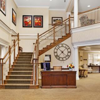 A welcoming lobby area with a staircase, reception desk, large wall clock, and decorative artwork.