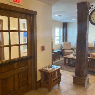 A cozy waiting area with comfortable seating and a wooden door, featuring warm lighting and modern decor.