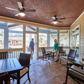 A spacious screened porch with furniture and ceiling fans, featuring two people enjoying the area.