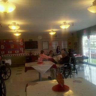 A group of elderly individuals socializing in a nursing home common area.
