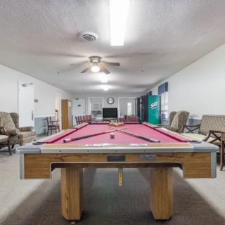 A recreation room featuring a pool table with pink felt and various seating options.