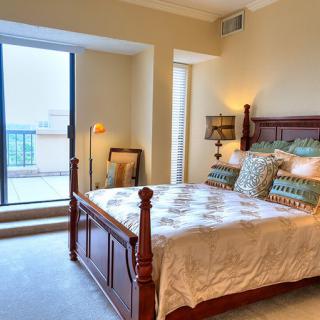 A cozy bedroom with a wooden bed, decorative pillows, and a view of the balcony.