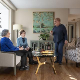 Three people engaging in conversation in a cozy living room.