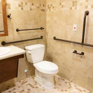 An accessible bathroom with grab bars and a tiled interior.
