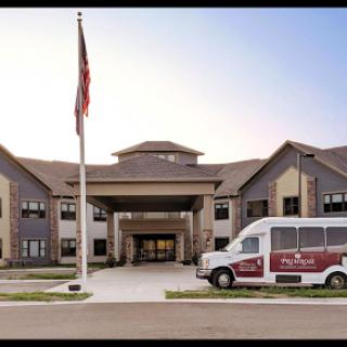 An inviting entrance to a residential healthcare facility, featuring a flagpole and transportation van.