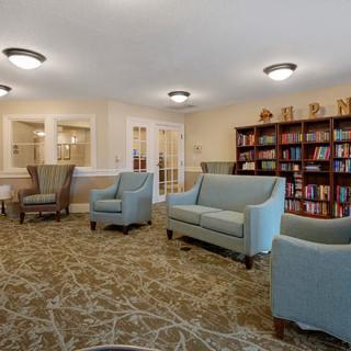 A cozy library seating area with armchairs and couches, surrounded by bookshelves.